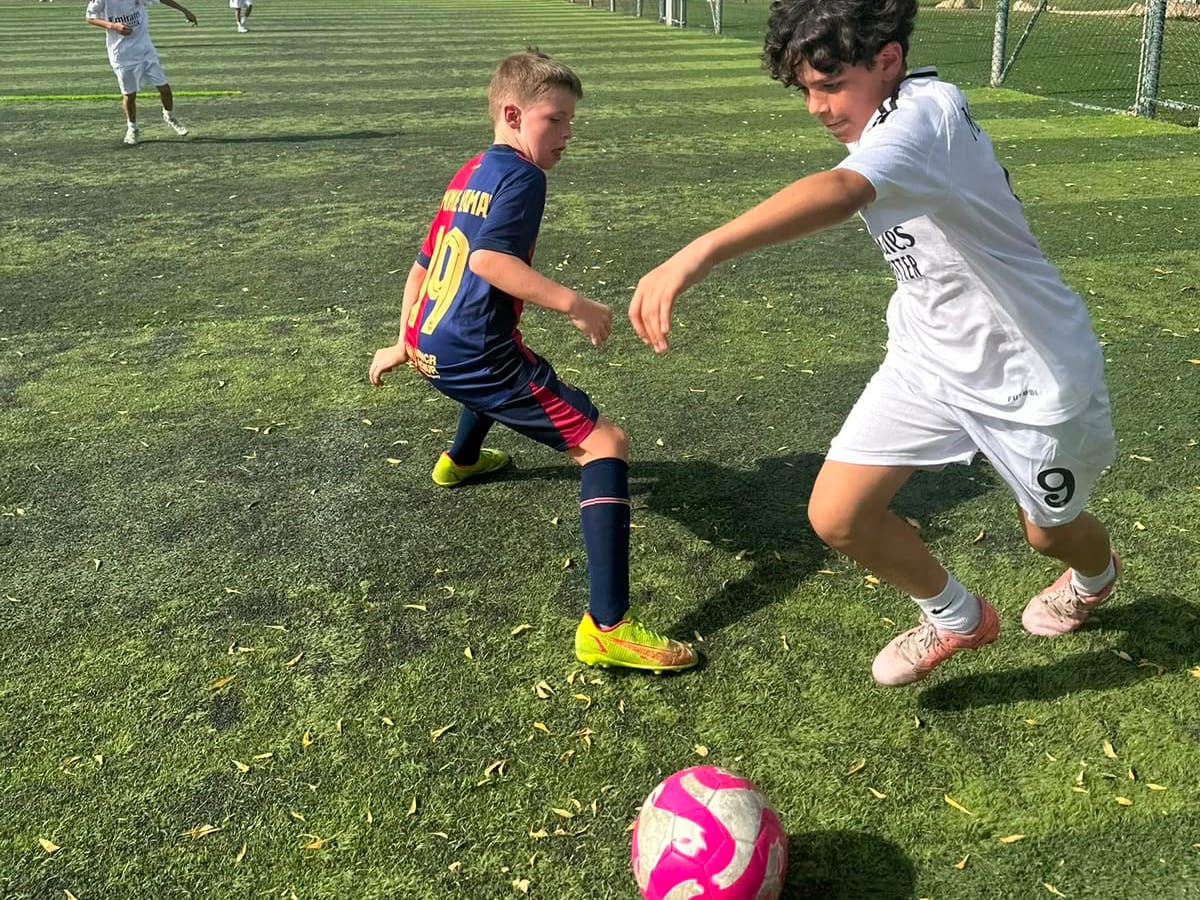 Two young players challenging for the ball during a Wolf Kids football session