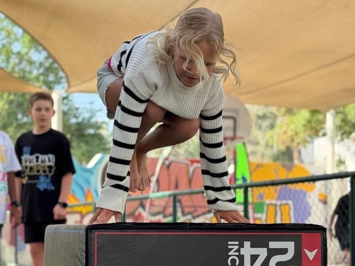 A child vaulting onto a padded box during a Wolf Kids parkour session