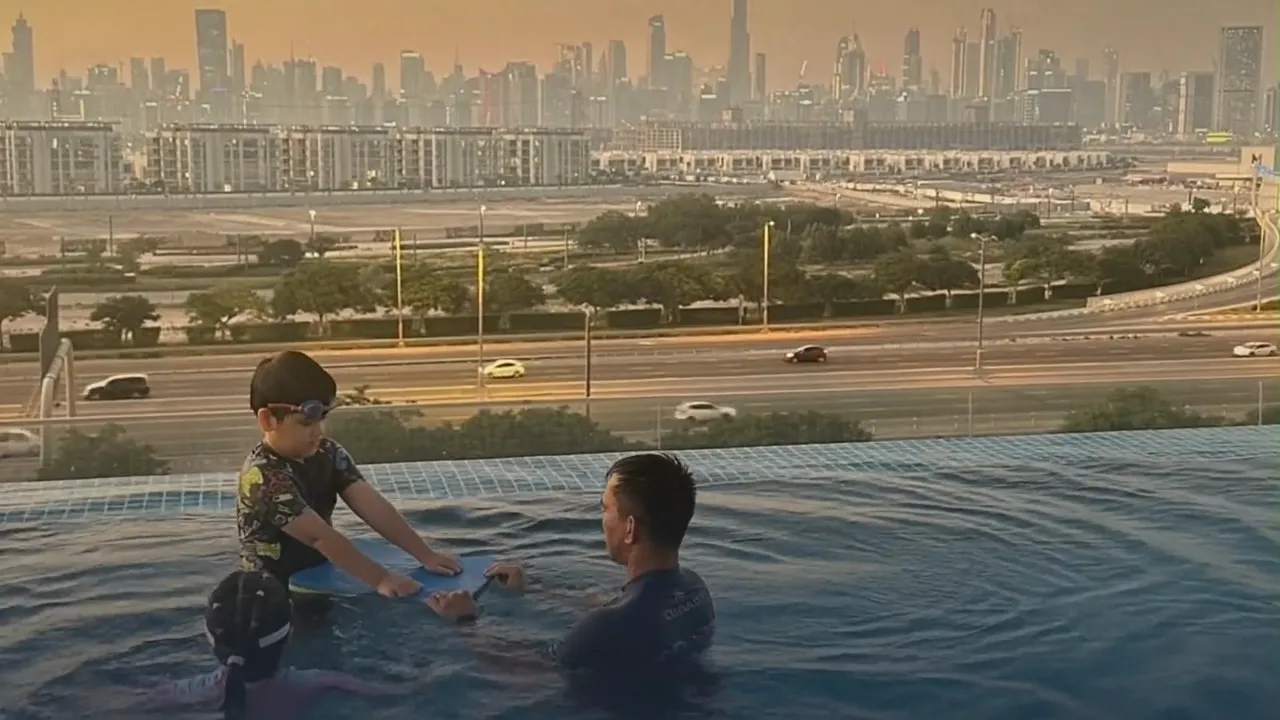 Wolf Kids children training in a Dubai park at sunset: a boy in a blue kit dribbles a football through orange cones while four teammates run an agility ladder beside their coach, with the city towers behind them.